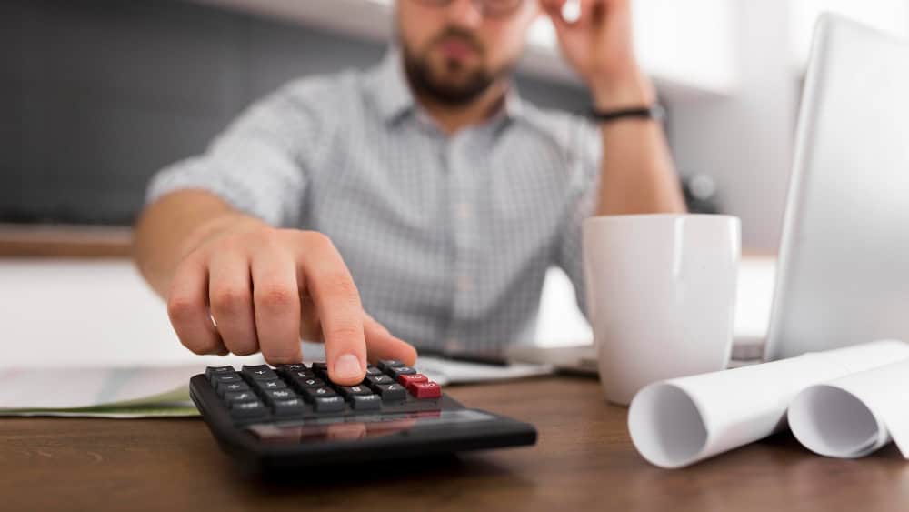 Close up of someone looking stressed using a calculator.