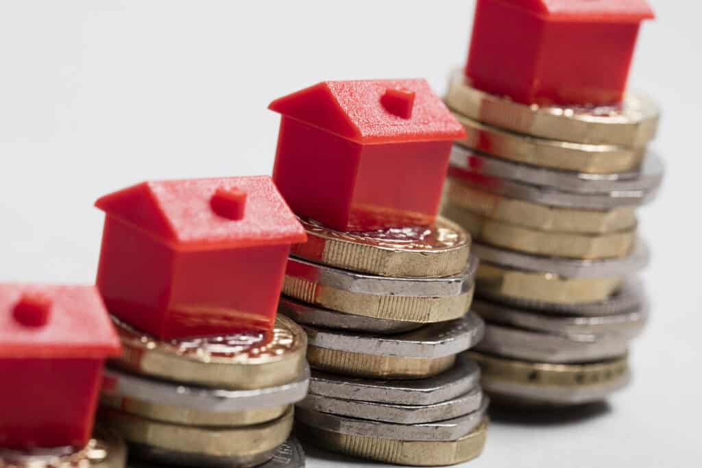 Monopoly houses on top of stacked coins.